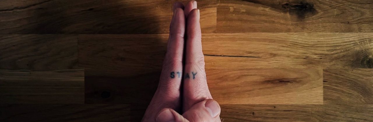 Mains pressées l'une contre l'autre, tatouage « STAY »
